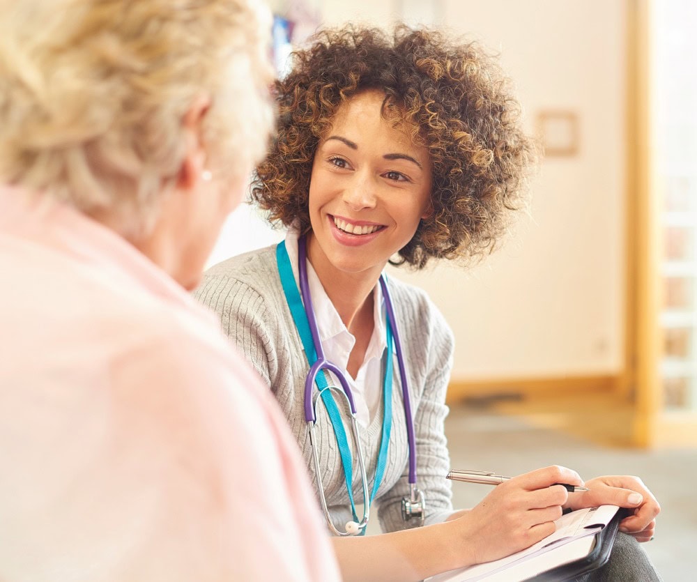 Medical technician taking notes and smiling at patient
